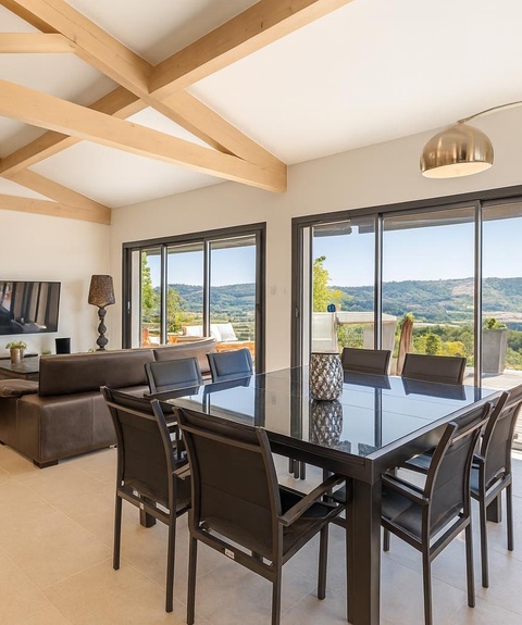 Superbe espace de vie lumineux avec salle à manger moderne, salon confortable et grandes baies vitrées offrant une vue panoramique spectaculaire sur les collines environnantes.